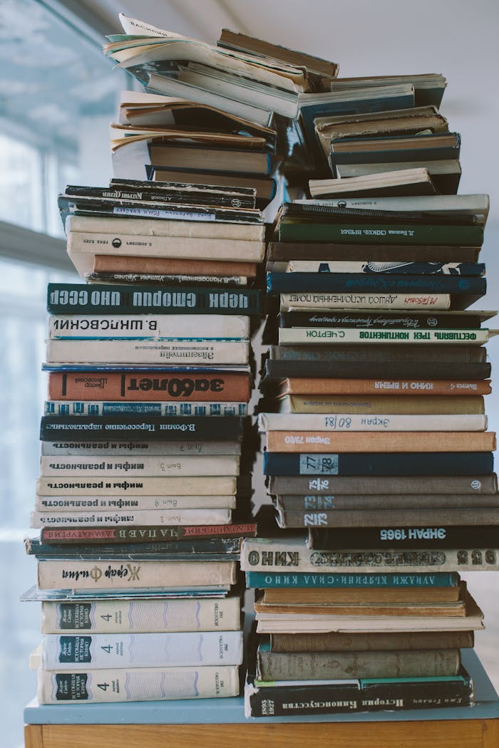 A tall, organized stack of hardcover books indoors, showcasing knowledge and study.